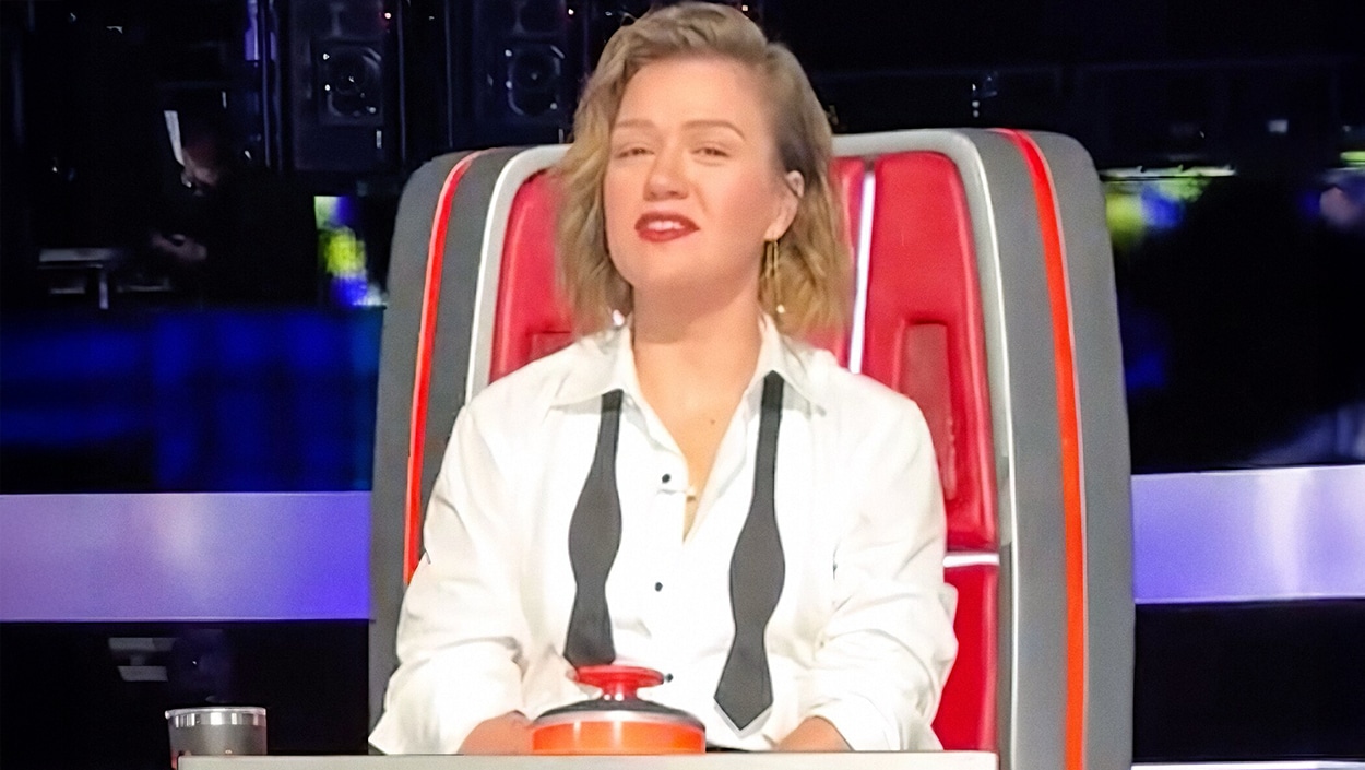 Kelly Clarkson sitting in a red chair on The Voice, leaning on her work for strength while moving forward from family heartbreak.