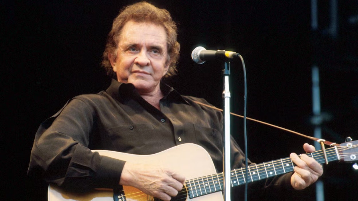 Country legend Johnny Cash onstage in black, his music and legacy continuing to shape generations long after his passing.