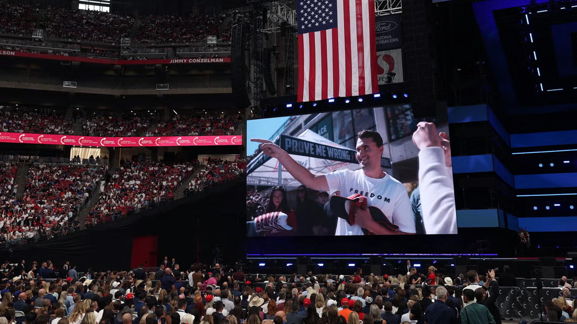 A packed State Farm Stadium with thousands gathered under the American flag for Charlie Kirk’s public memorial service.