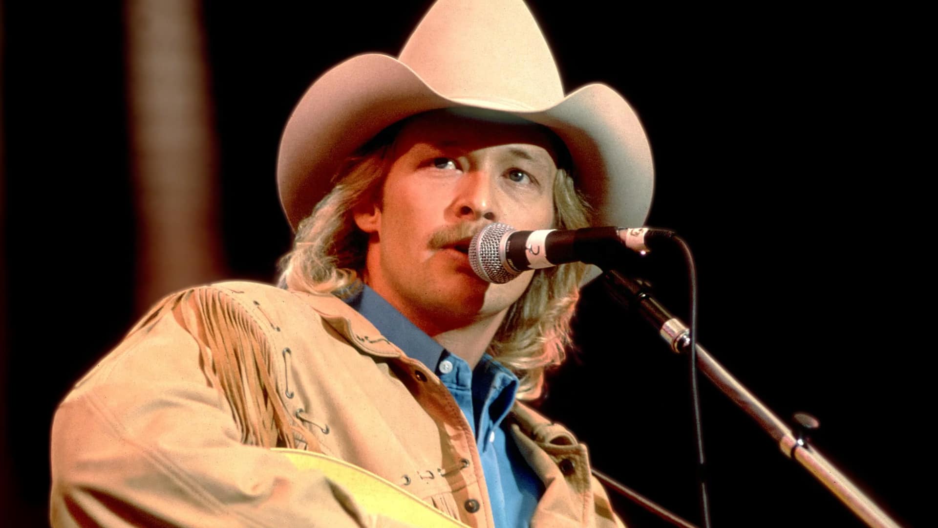 Alan Jackson at the microphone during a live performance, honoring the legacy of George Jones and Roger Miller, who originally wrote his chart-topping song “Tall, Tall Trees.”