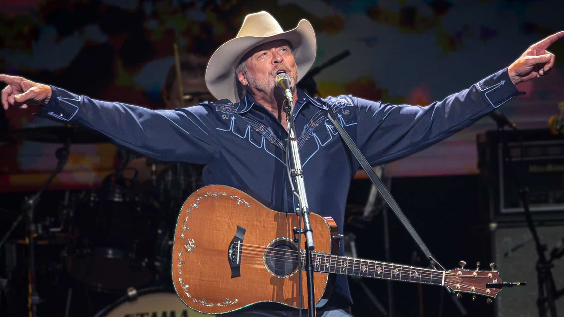 Alan Jackson performing onstage with his guitar and cowboy hat, teasing a star-studded farewell concert lineup featuring some of country music’s biggest names.