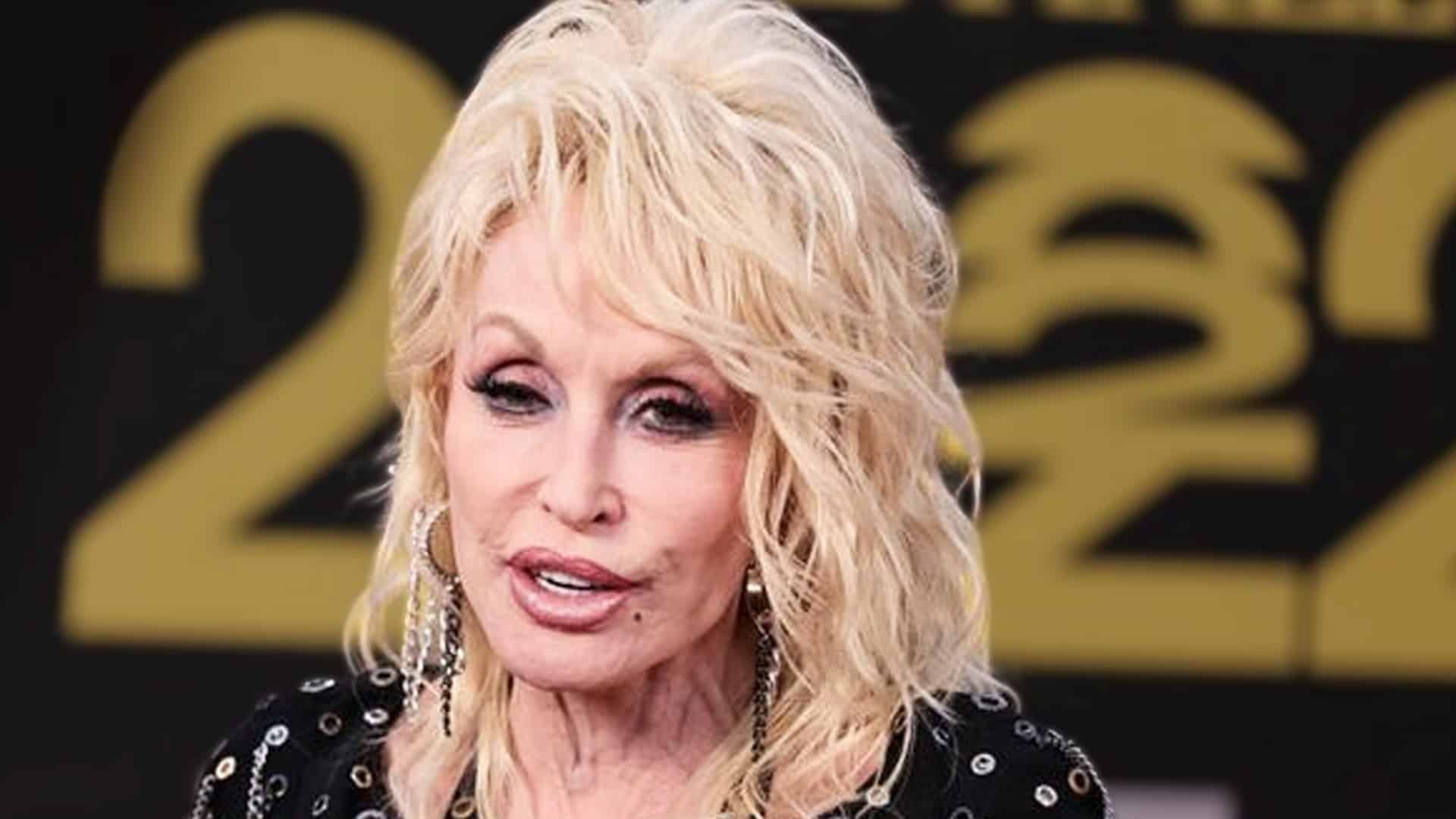 Dolly Parton on the red carpet in a black sequined outfit, as her team’s comment about her health being “just kidney stones” sparks fan backlash.