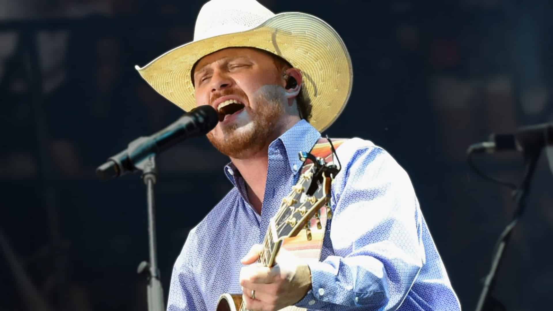 Cody Johnson singing on stage with his guitar and cowboy hat, amid fan buzz about his long-awaited cover of “Travelin’ Soldier.”