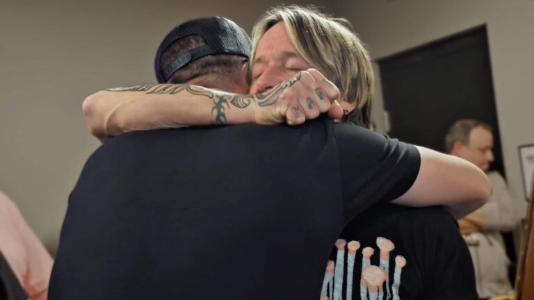 Keith Urban and Chase Matthew sharing an emotional hug backstage after Chase surprised him with a custom phoenix-themed guitar for his birthday.
