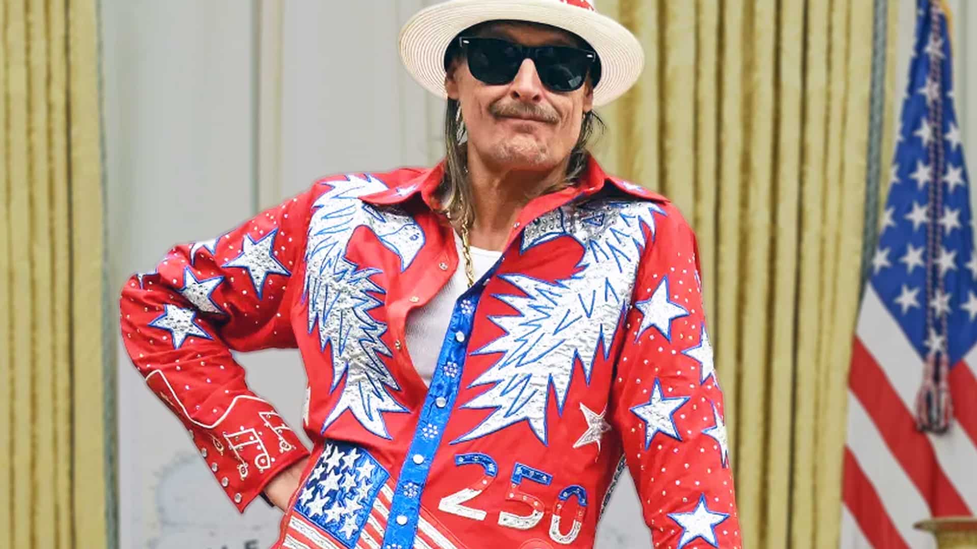Kid Rock wearing a patriotic red, white, and blue outfit with stars and eagles, posing confidently as he talks about wanting to perform in the White House’s new ballroom.
