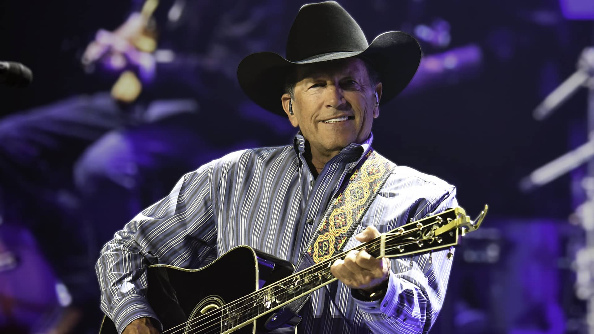 George Strait smiling mid-performance, as a growing petition calls for him to replace Bad Bunny at the Super Bowl halftime show.