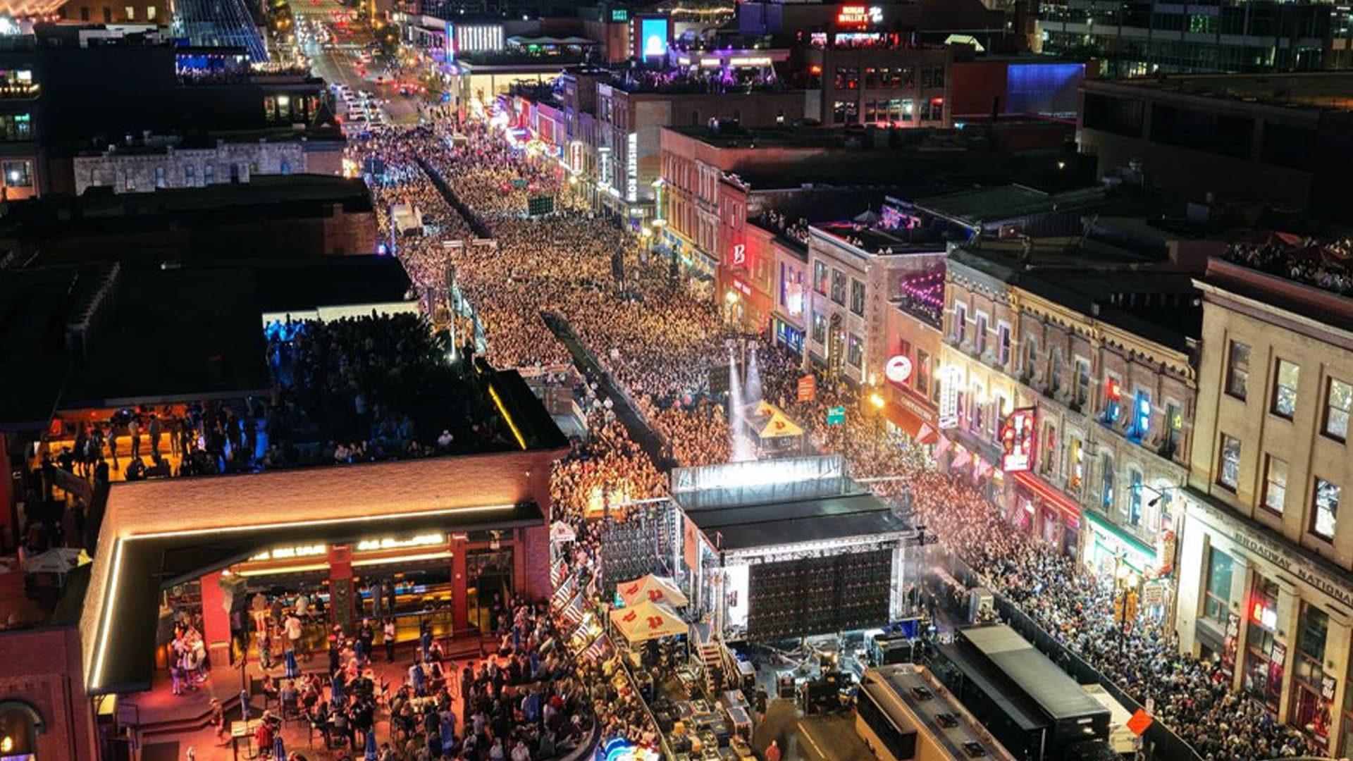 Massive crowd fills Nashville’s Lower Broadway at night for the grand opening of Post Malone’s bar, Posty’s, with live music and neon lights glowing.
