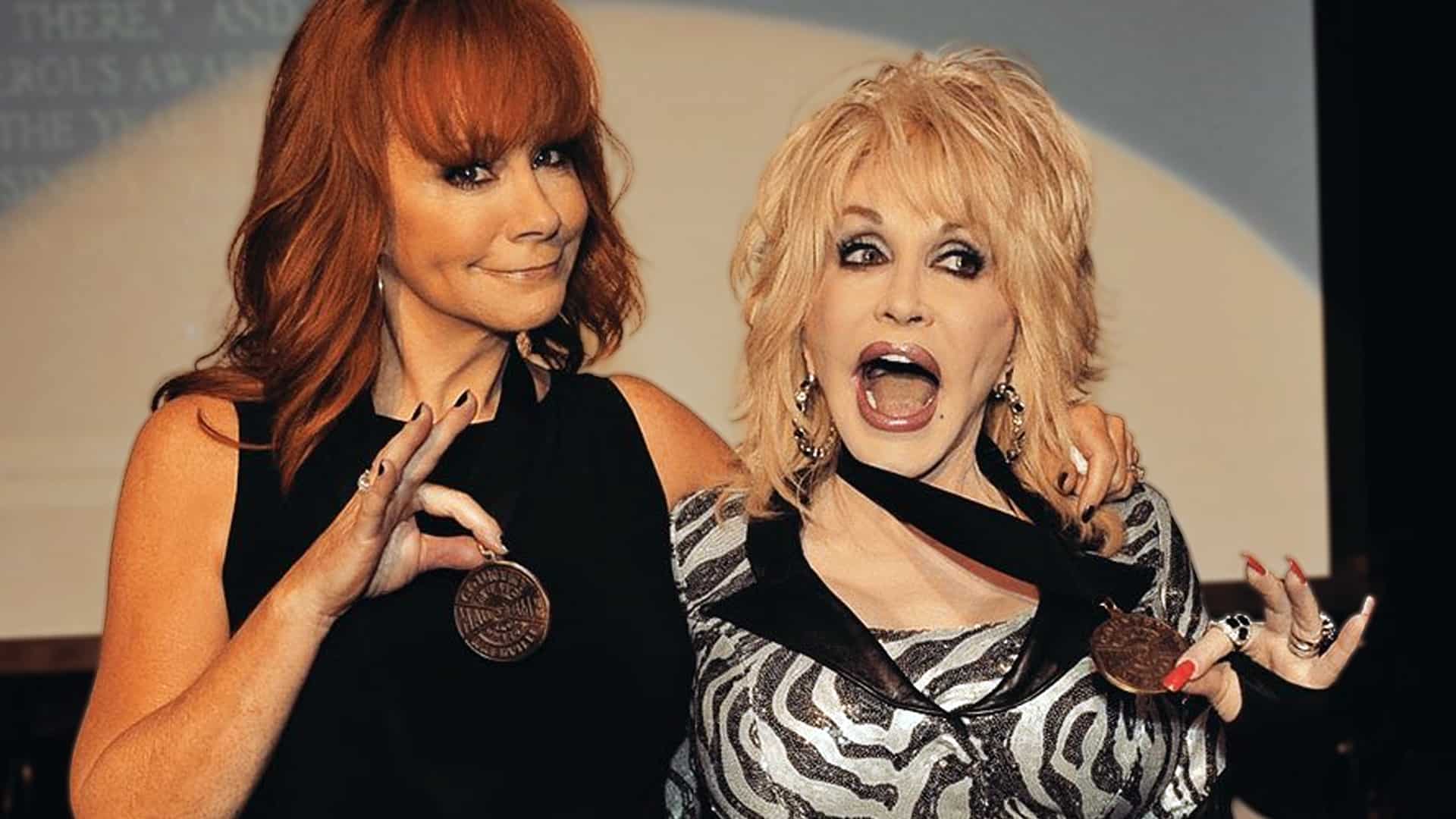 Reba McEntire and Dolly Parton sharing a playful moment with their medals, celebrating friendship and their shared refusal to retire from country music.