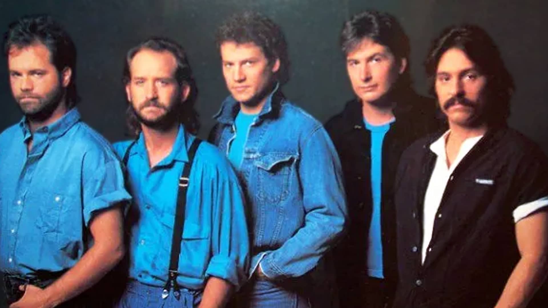 Restless Heart posing together in denim and blue tones, the country band behind the timeless love ballad “I’ll Still Be Loving You.”