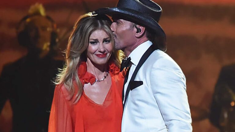 Tim McGraw kissing Faith Hill’s forehead onstage as she appears emotional, following his revelation about her years of health struggles and multiple surgeries.