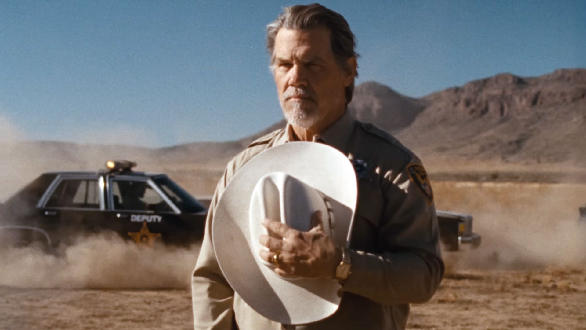 Josh Brolin as a rugged sheriff holding his hat in the desert, starring in Chris Stapleton’s cinematic “White Horse” music video.