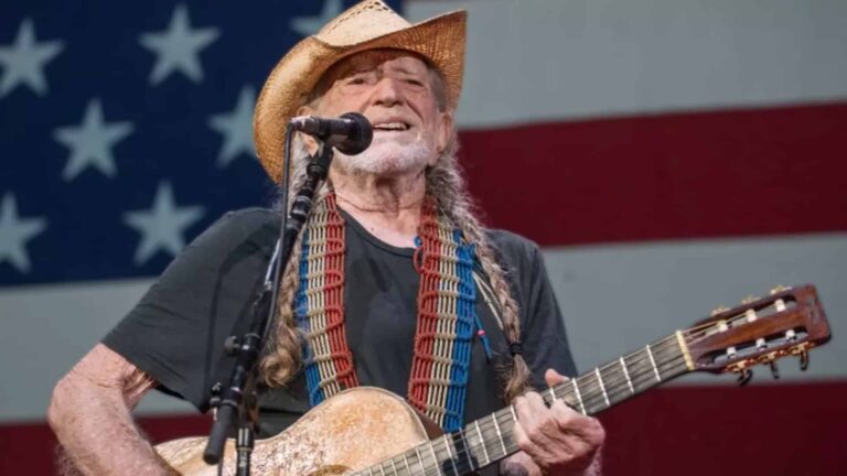 Country legend Willie Nelson smiling onstage with his guitar, honoring his roots as a U.S. Air Force veteran despite persistent draft rumors.