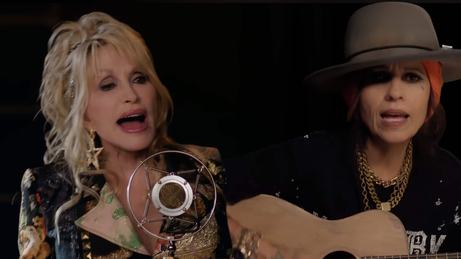 Dolly Parton and Linda Perry perform together, with Dolly singing into a vintage microphone and Linda playing guitar, during their emotional duet of “What’s Up?” that went viral online.
