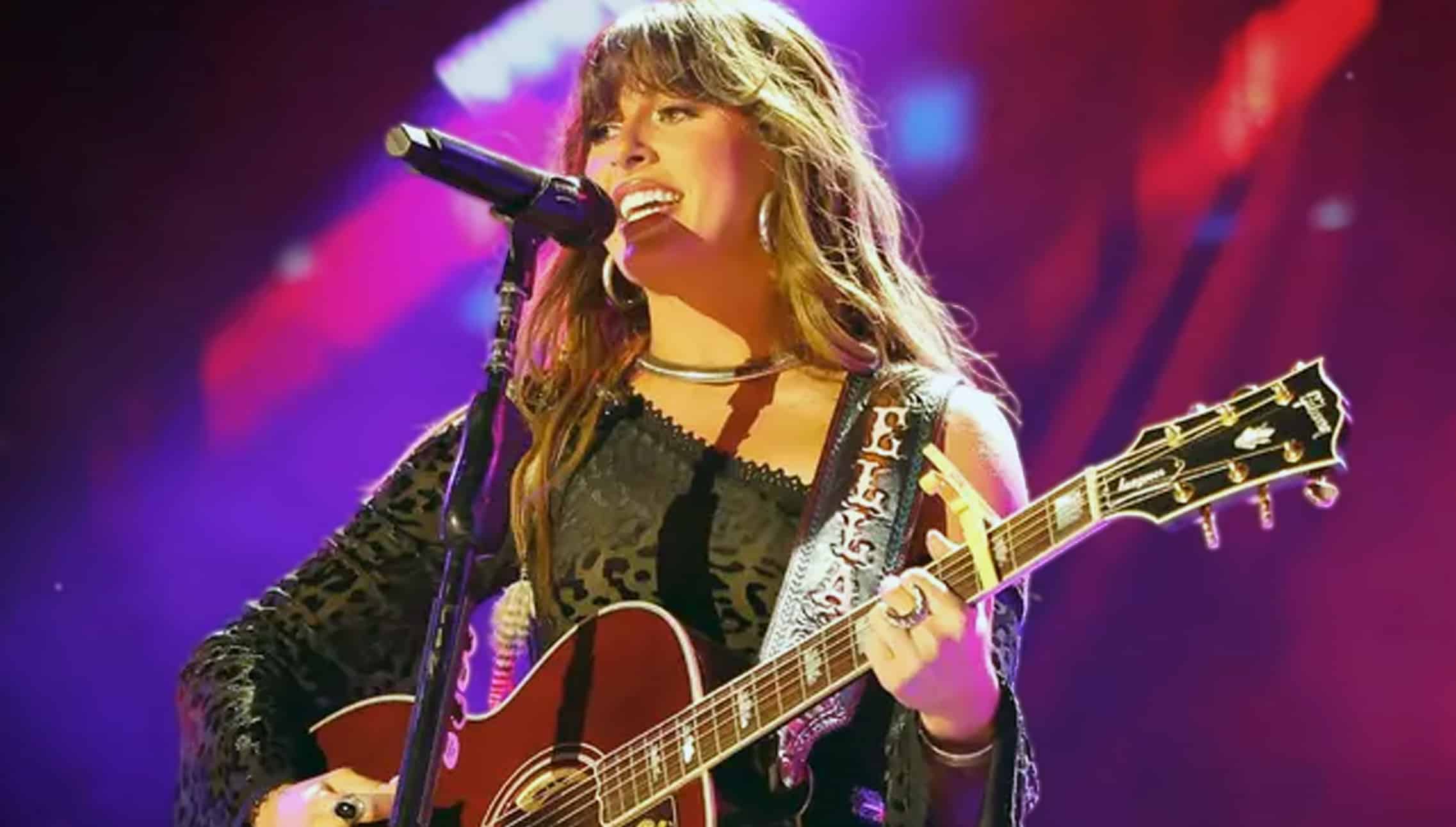 Ella Langley smiling mid-performance in black lace and fringe vest, revealing the hilarious moment her team said “enough” over her candle obsession while celebrating new house, awards, and major tours.