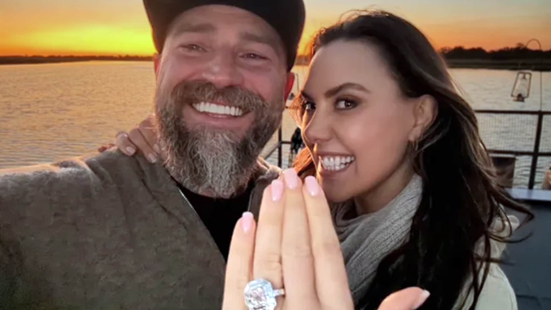 Kendra Scott and Zac Brown pose on a sunset boat ride, both beaming as she displays her pink diamond engagement ring following his proposal.