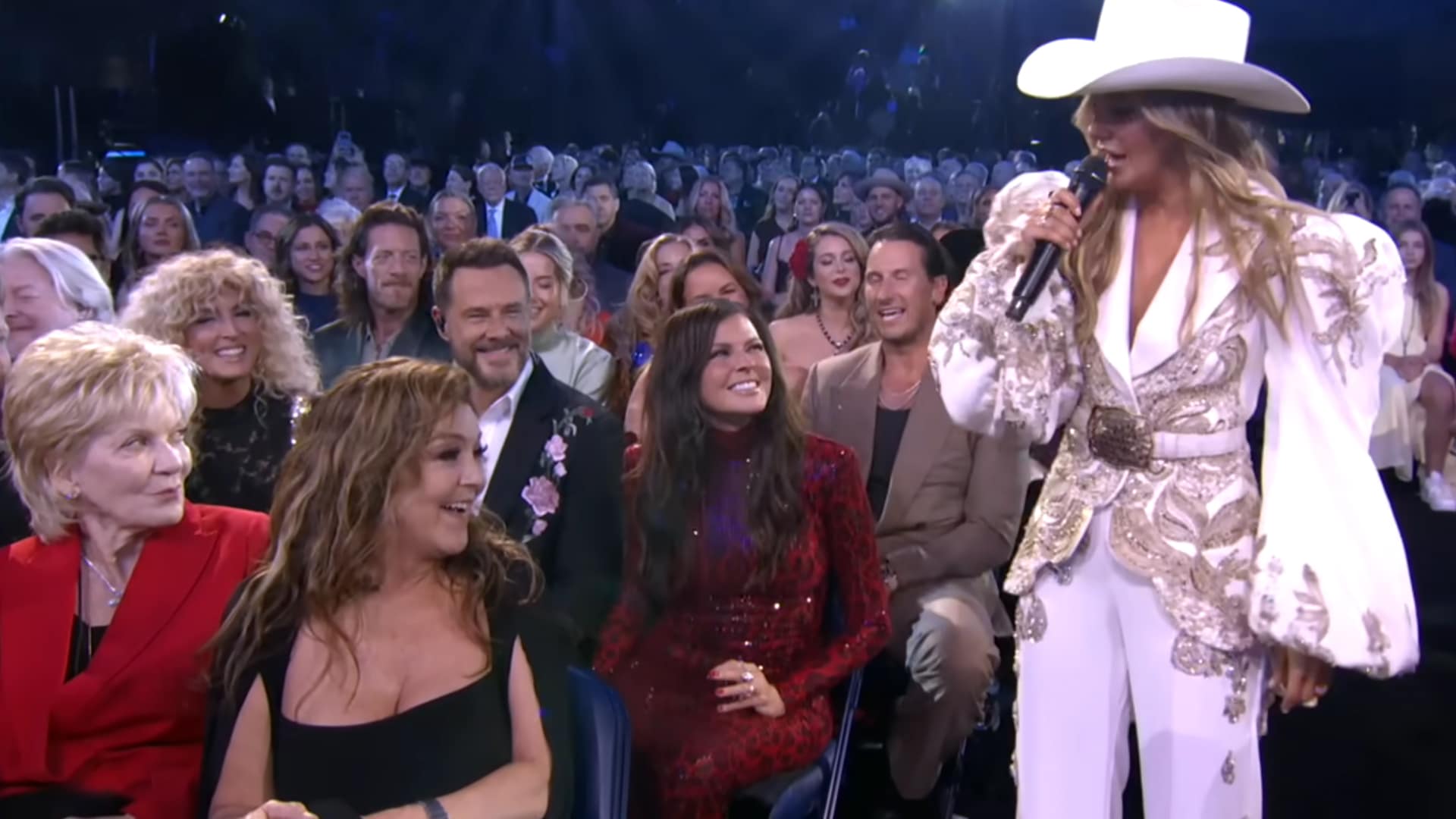 Lainey Wilson performs fiery CMA Awards medley in white cowboy hat and embroidered white suit with Keith Urban Miranda Lambert and legends cheering.