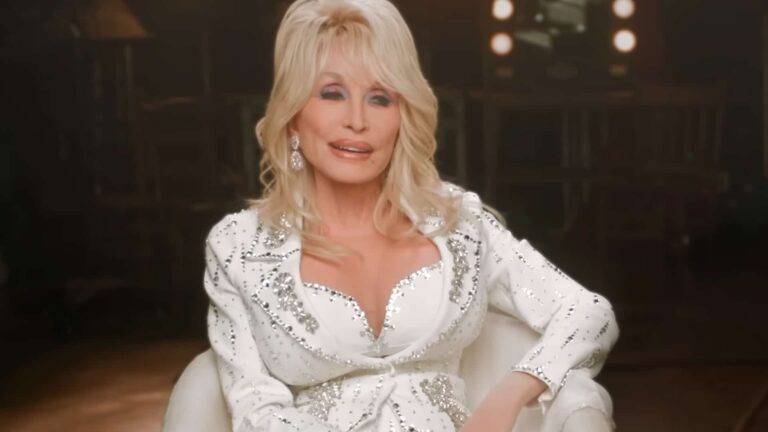 Dolly Parton seated in a rhinestone jacket, capturing the same fearless sparkle she showed when she teased June Carter about Johnny Cash.
