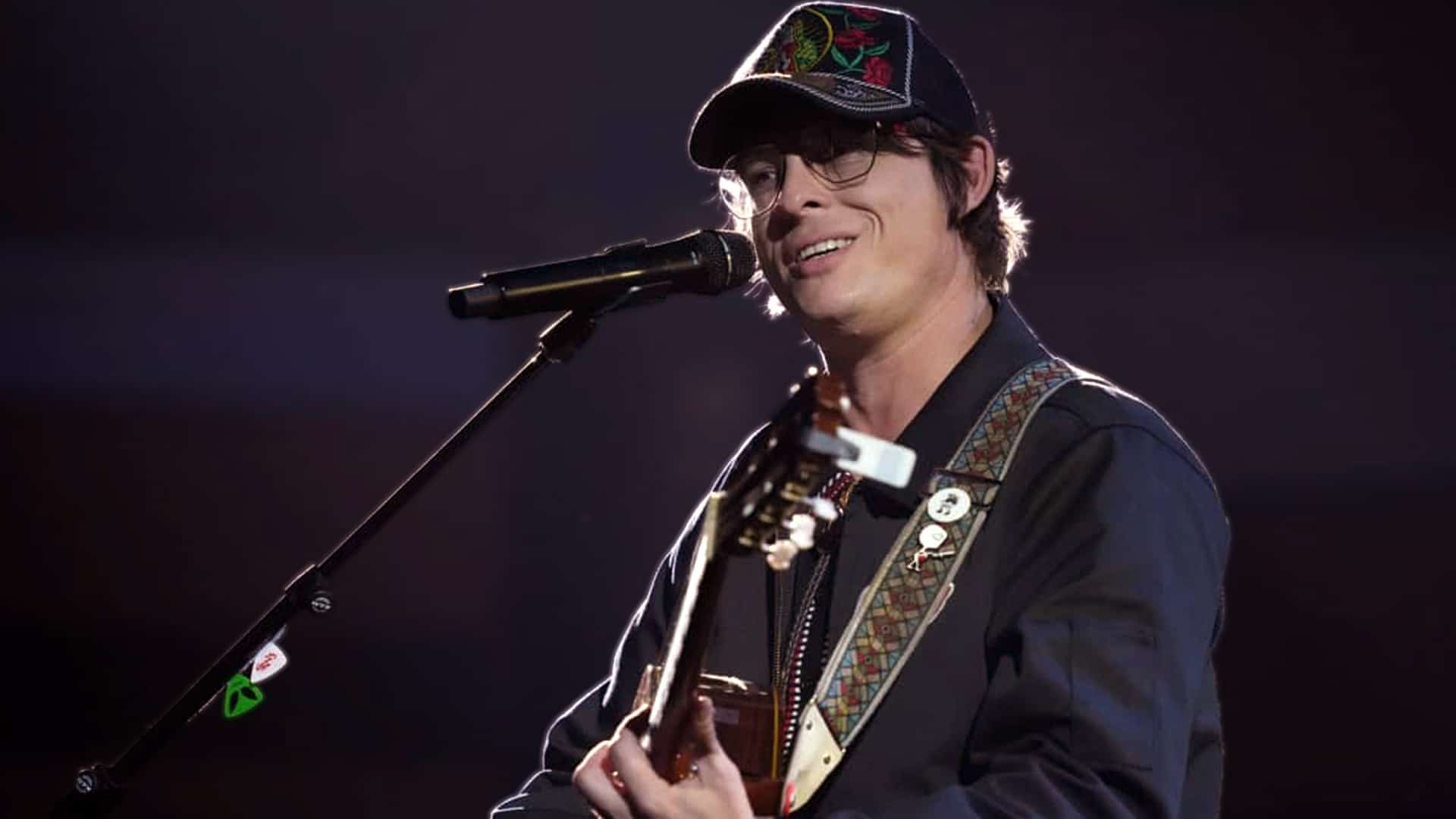 Close-up of Stephen Wilson Jr. on stage with guitar and microphone, exuding authentic outlaw country energy in a black cap and glasses during his viral CMA Awards performance that launched the 46-year-old Indiana boxer-turned-musician into stardom.