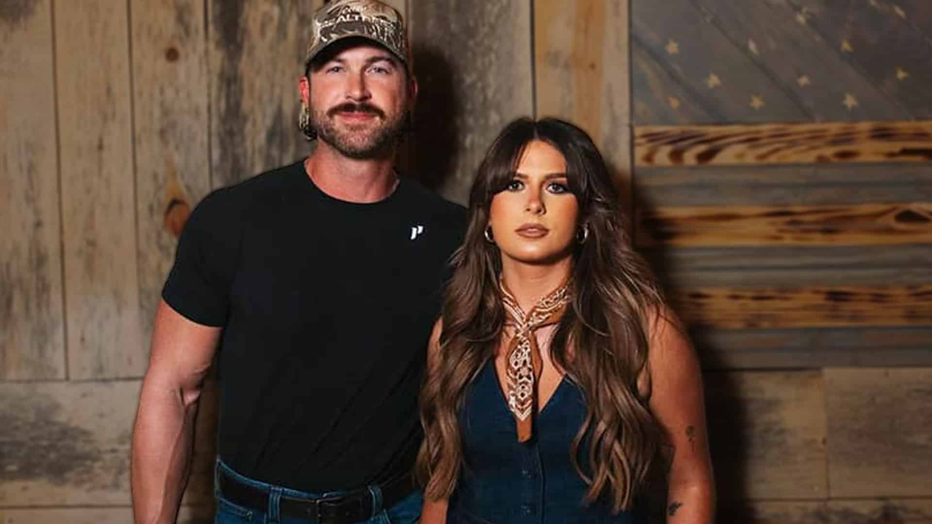 Ella Langley in denim dress with scarf and Riley Green in black t-shirt and camo cap standing together celebrating You Look Like You Love Me earning seven CMA and ACM Awards including historic 2025 CMA single song and video sweep.