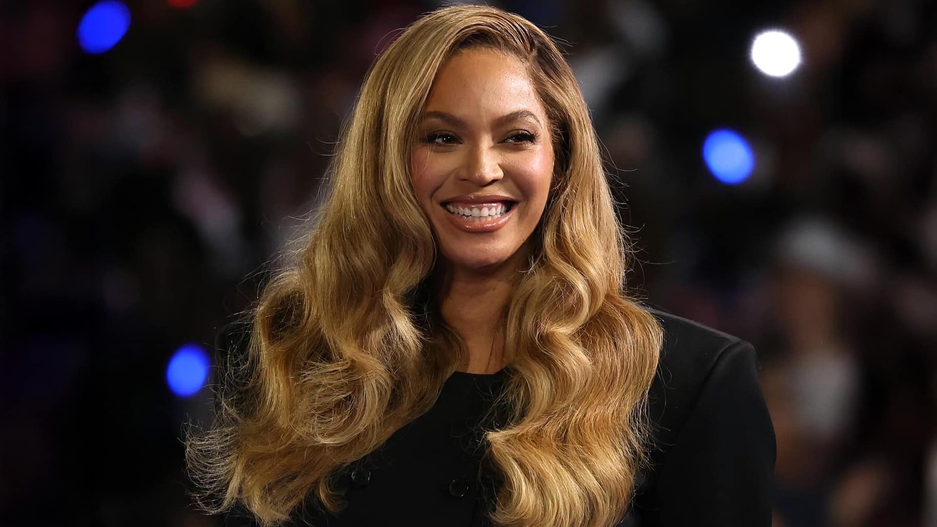 Beyoncé smiles on stage with long blonde hair and black outfit, officially becoming a billionaire according to Forbes 2025 report, building her empire through pop music, Renaissance Tour, and ventures beyond her Cowboy Carter country era.