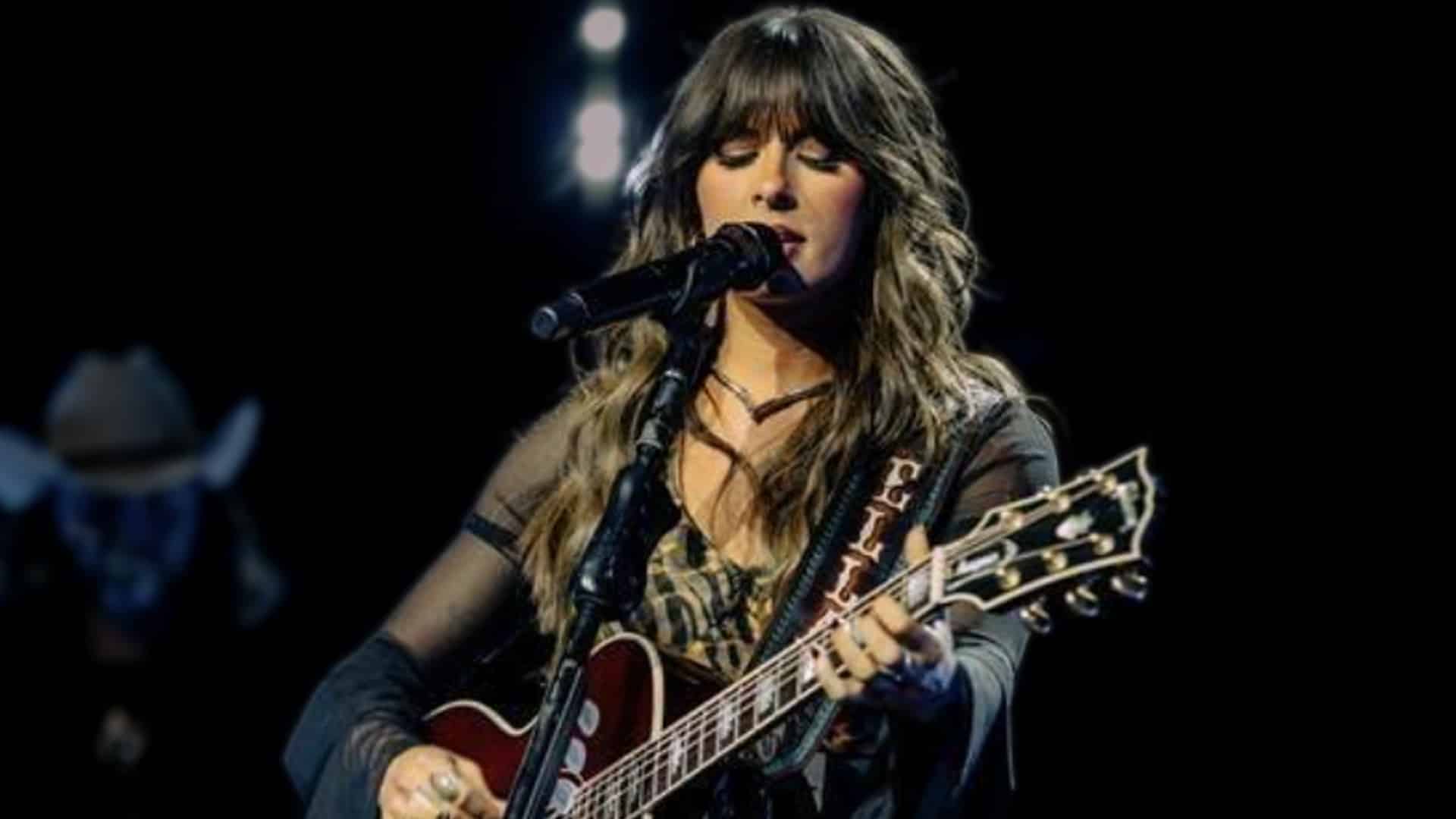 Ella Langley performs a powerful cover of Kitty Wells' "It Wasn't God Who Made Honky Tonk Angels" on stage in black fur-trimmed jacket and guitar, honoring the 1952 country trailblazer with raw emotion and flawless vocals during her 2025 Texas headlining show.