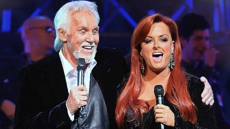 Kenny Rogers and Wynonna Judd perform the modern Christmas classic "Mary Did You Know?" on stage, capturing the powerful duet that helped popularize the song written by Mark Lowry after seven years of searching for the perfect melody.