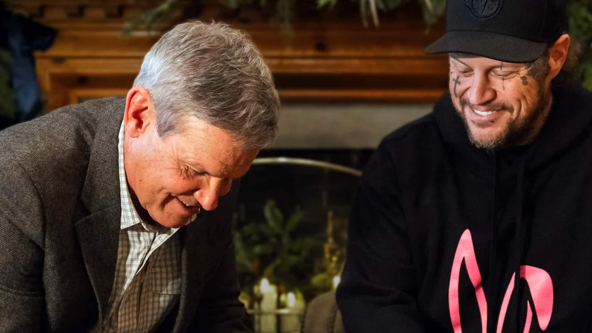 Jelly Roll shares a joyful moment with Tennessee Governor Bill Lee after receiving a full pardon in 2025, Jelly smiling in black cap and hoodie with tattoos, marking a redemption milestone from his prison past to country music stardom.