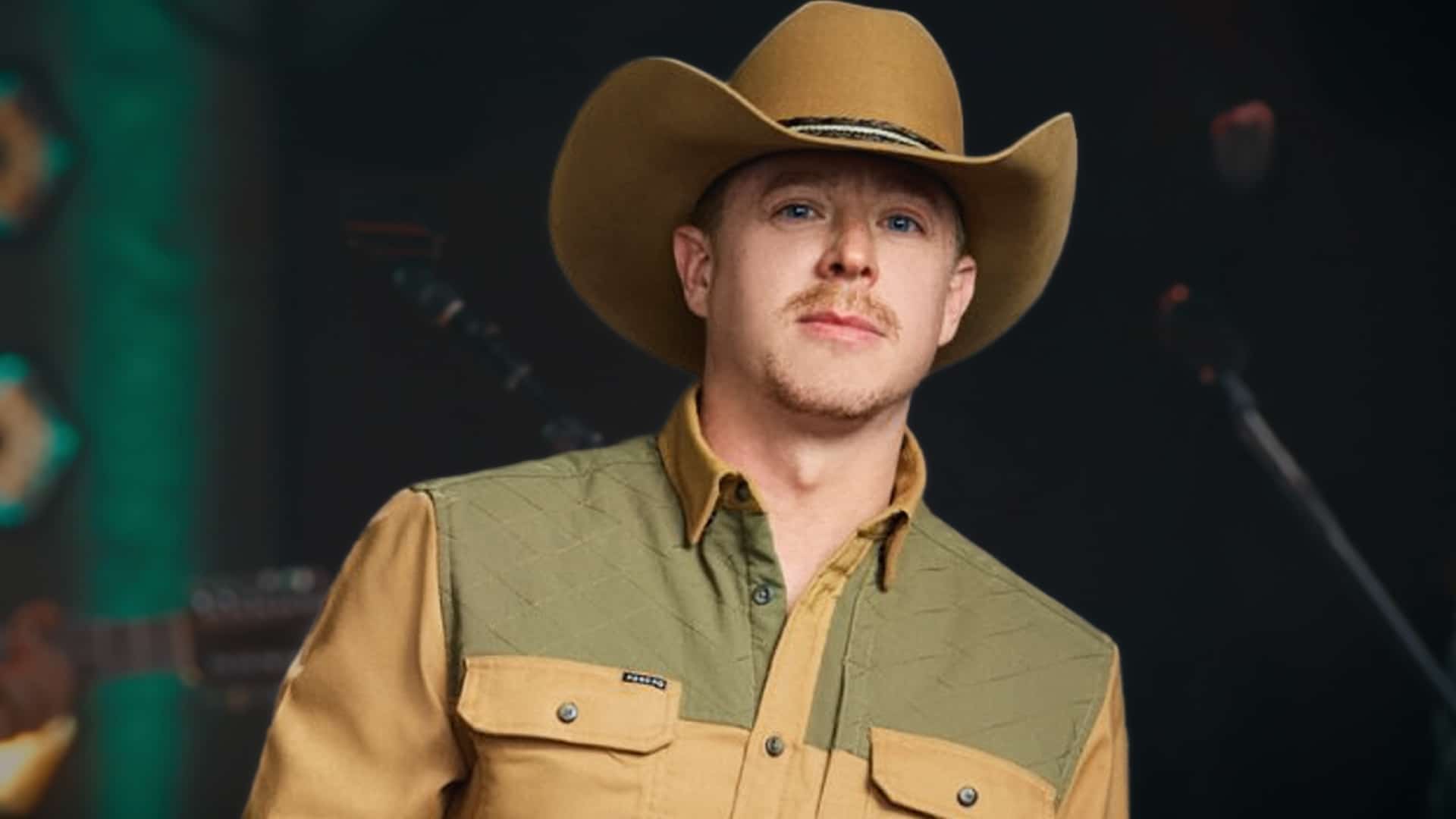 Adam Sanders, winner of Keith Urban's CBS competition The Road, stands on stage in tan cowboy hat and quilted shirt, taking home $250,000, a record deal, and Stagecoach slot after beating finalists at Nashville's Ryman Auditorium in December 2025.