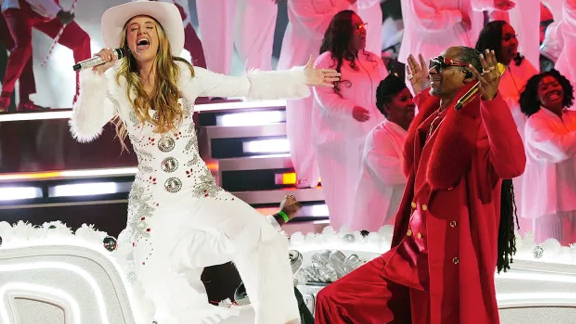 Lainey Wilson performs "Santa Claus is Coming to Town" with Snoop Dogg at the 2025 NFL Christmas halftime show in white cowboy hat and fur-trimmed outfit, arriving on a sleigh for a festive country spectacle during the Vikings-Lions game.