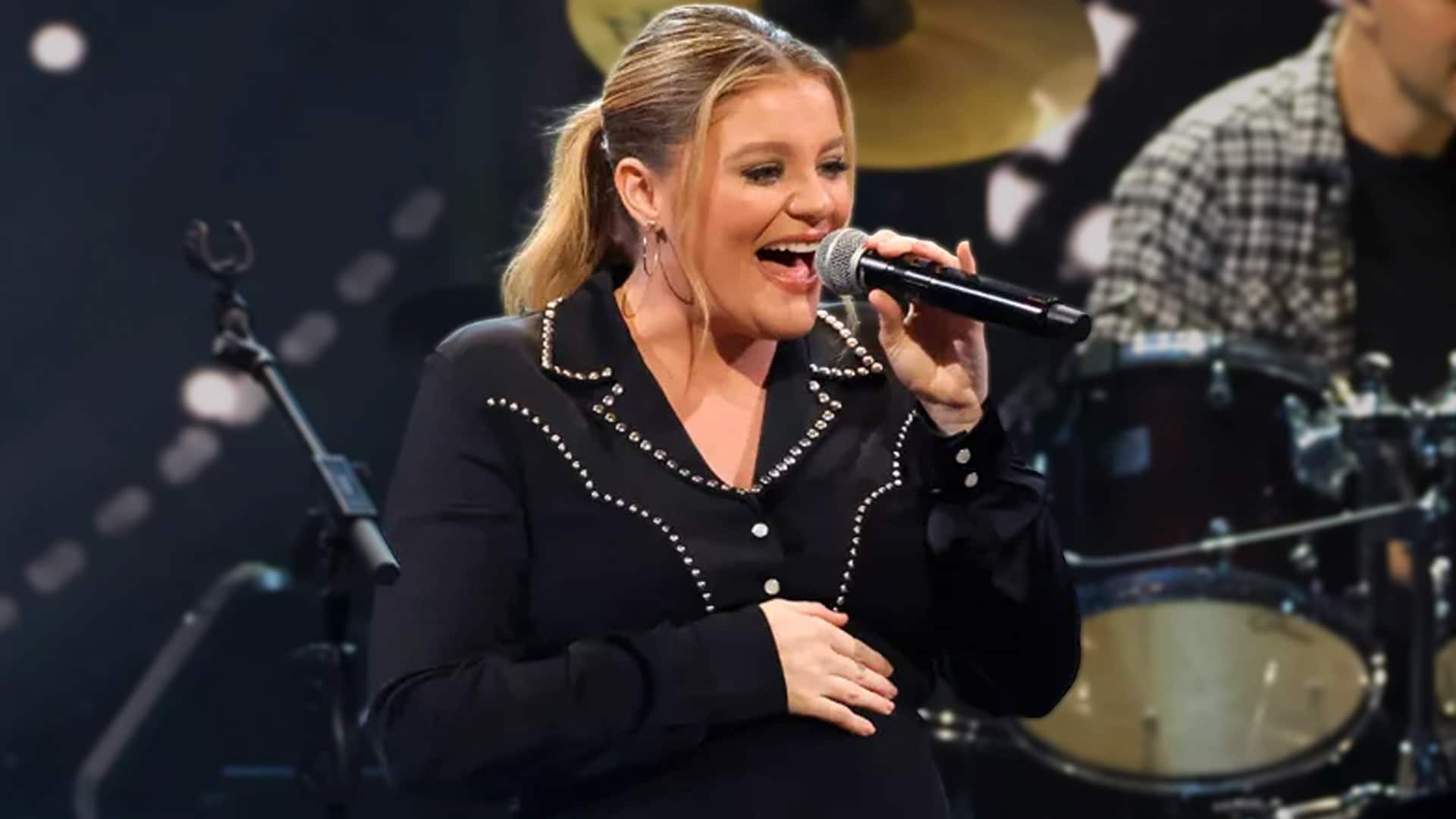Lauren Alaina performs on stage in a classic photo wearing a black studded shirt with ponytail, as she shares a hilarious 2025 wardrobe mishap of mismatched black and brown boots before her Ohio concert with Chase Matthew.