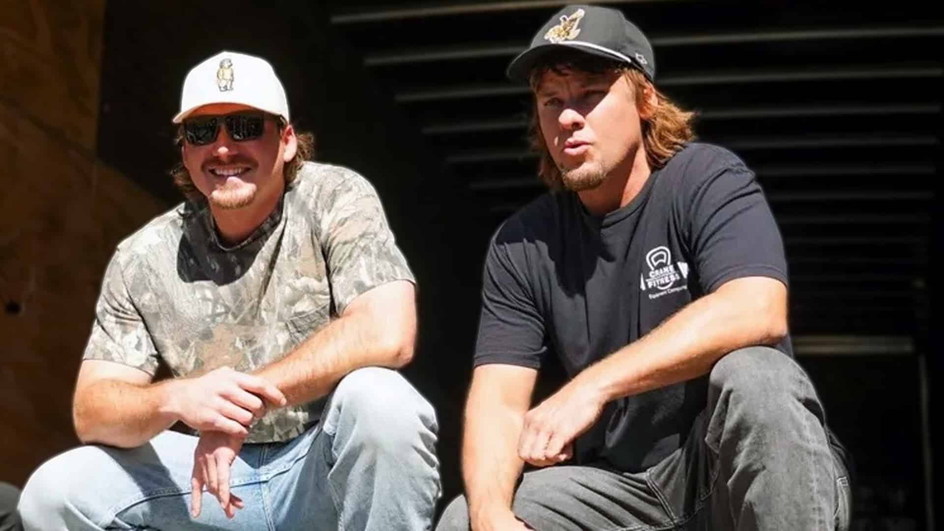 Theo Von and Morgan Wallen sit together casually, Theo in camo shirt and white cap, Morgan in black cap and Crane Fitness tee, as Theo reveals on his podcast they're in a Bible study group, showing a wholesome side of the country star in 2025.