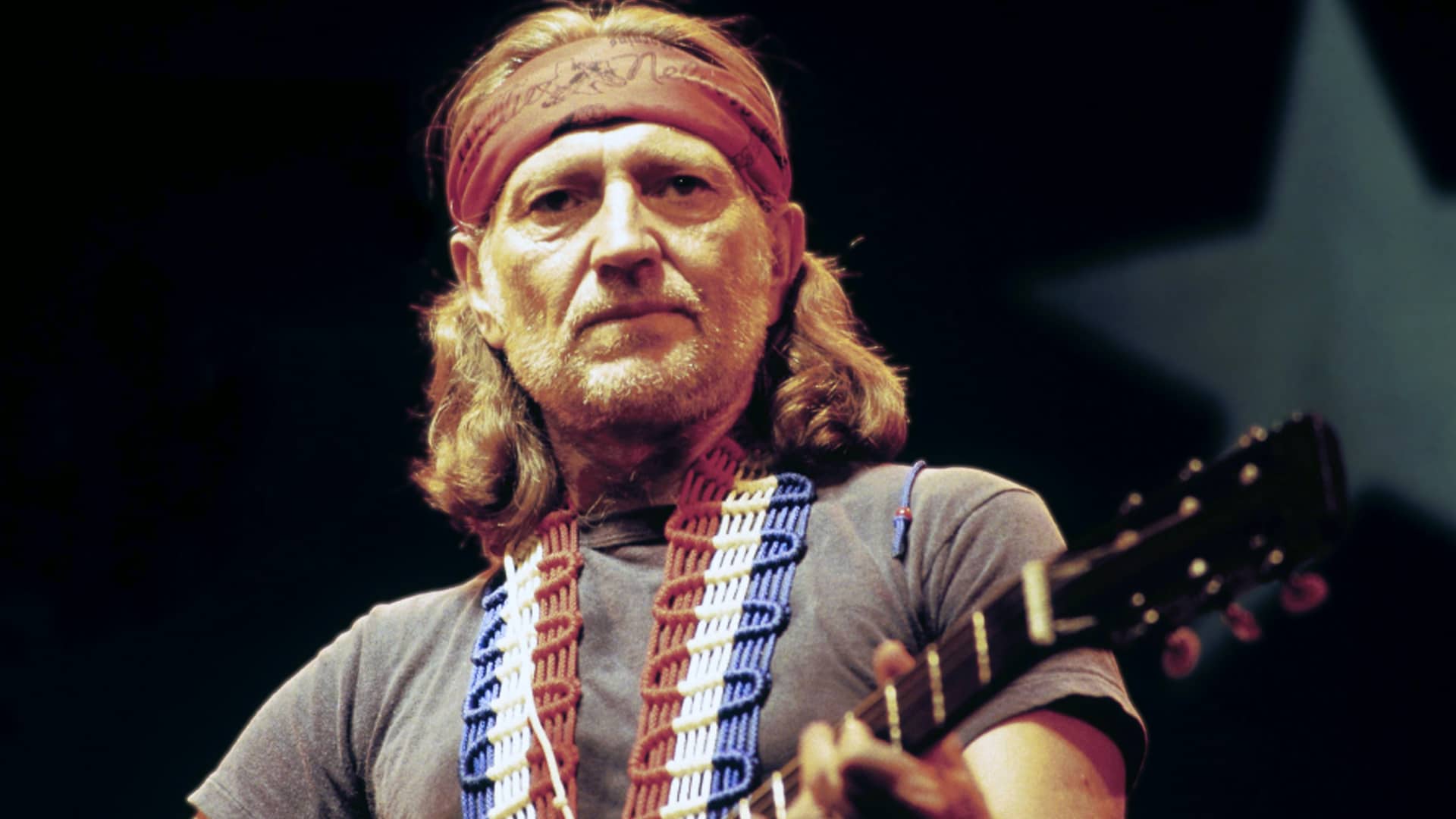 Willie Nelson in his iconic 1970s outlaw era with red bandana and guitar strap on stage, after attempting to quit music in 1972 only to return stronger with Shotgun Willie and spark the Texas country revolution in Austin.