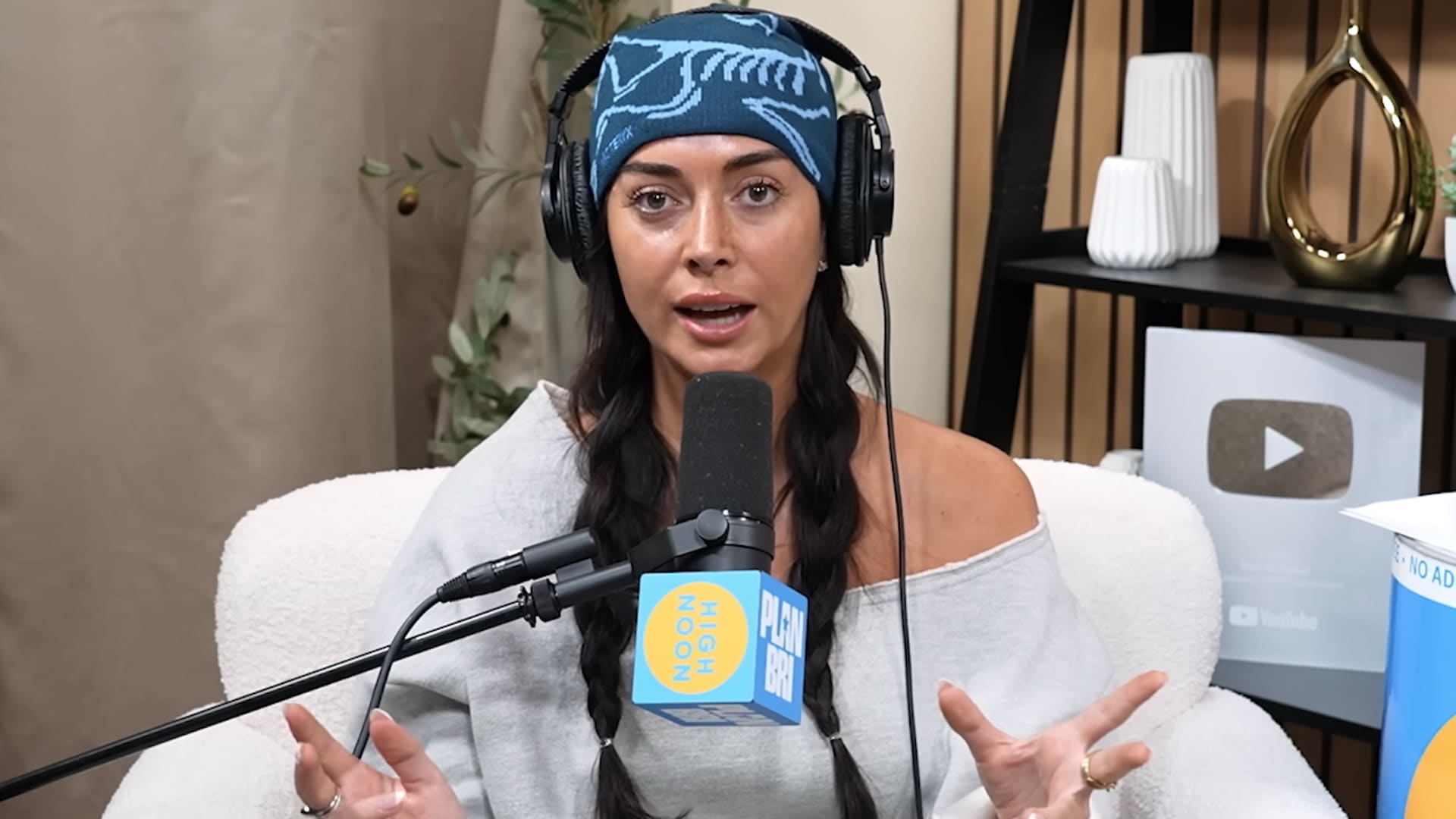 Brianna Chickenfry (Brianna LaPaglia) speaks emotionally on Plan Bri podcast wearing headphones and blue beanie, revealing in 2026 episode deep sexual trauma from her relationship with Zach Bryan and desire to move on.