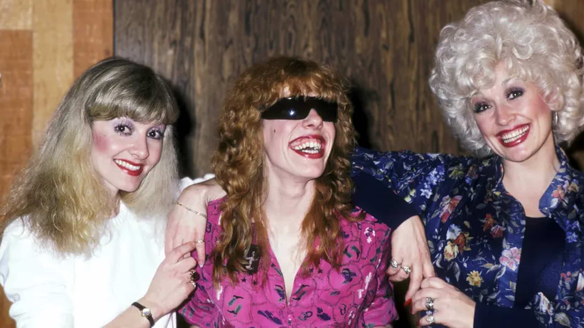 Freida Parton with sisters Dolly Parton in sunglasses and pink blouse and Stella Parton in blue floral top smiling together in vintage photo, as Freida clarifies her viral 2025 prayer request for Dolly was out of love and faith during her recovery, not alarm.