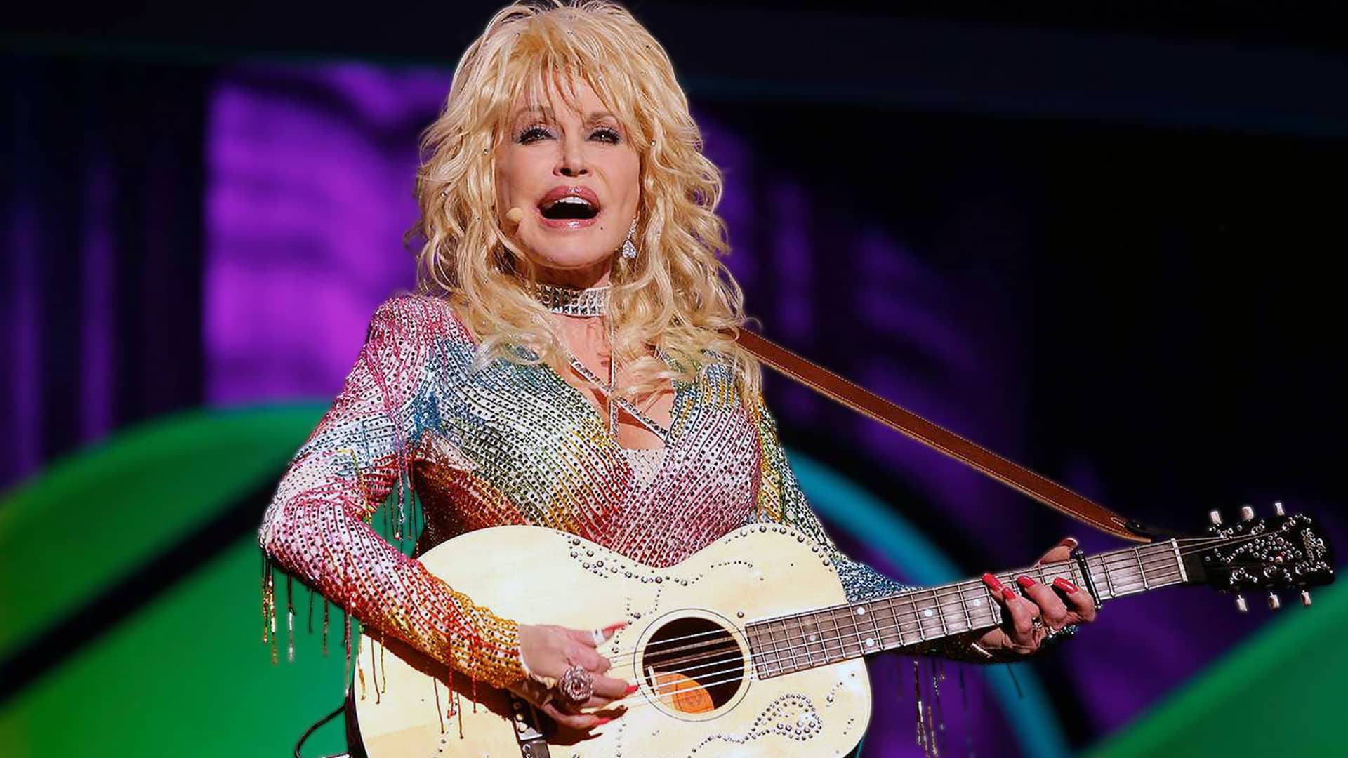 Dolly Parton sings onstage in a rhinestone outfit, embodying the timeless star power celebrated with her official Dolly Parton Day.
