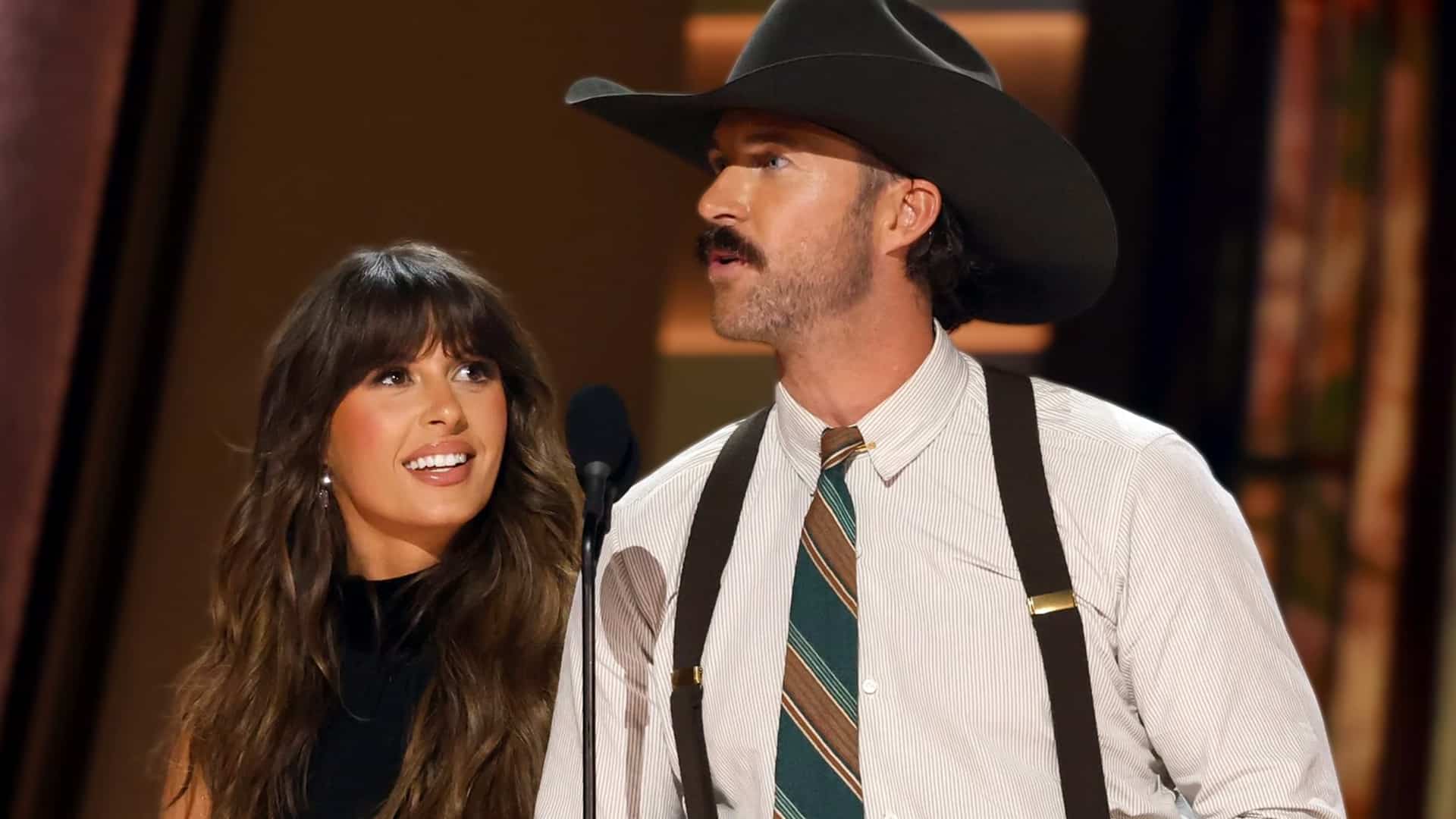 Riley Green on stage in black cowboy hat and striped shirt with suspenders next to Ella Langley, breaking silence in 2026 to confirm he is single and clearing up ongoing dating rumors about his relationship status.