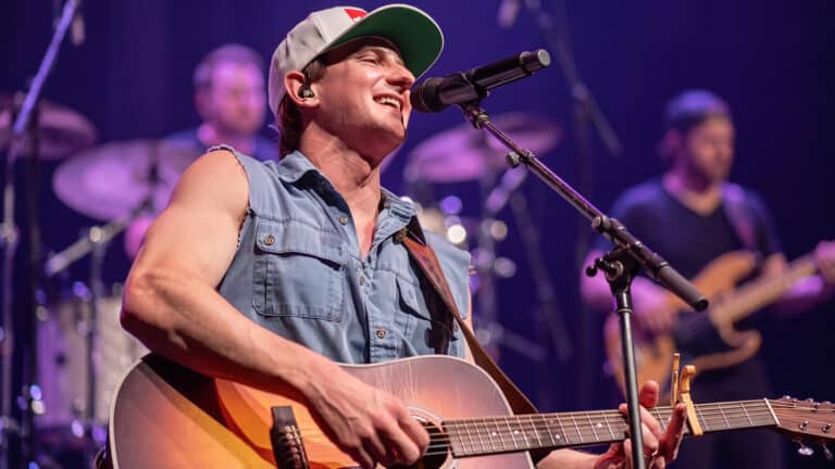 Cooper Alan sings on stage as he clarifies that his hometown never had a Dale Dickens, even as fans keep linking the name to “Goodbye Earl.”